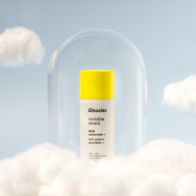 A beauty product with a glass container and clouds around it