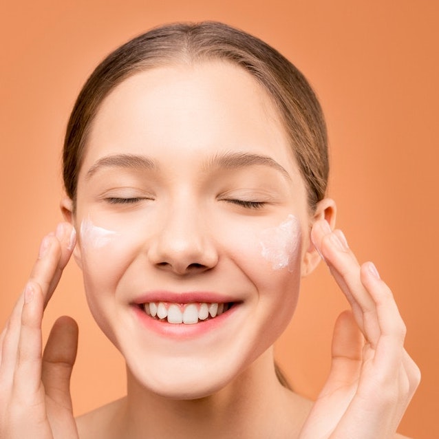 A lady applying moisturizer on her face