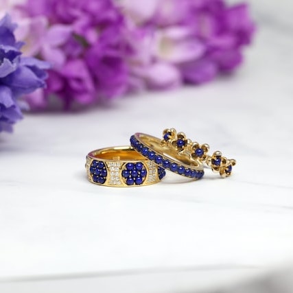Three rings with purple gems, with purple flowers in the background