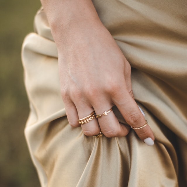 A hand with several rings, on a golden silky dress