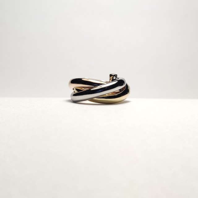 A gold and silver ring in a cream-white background