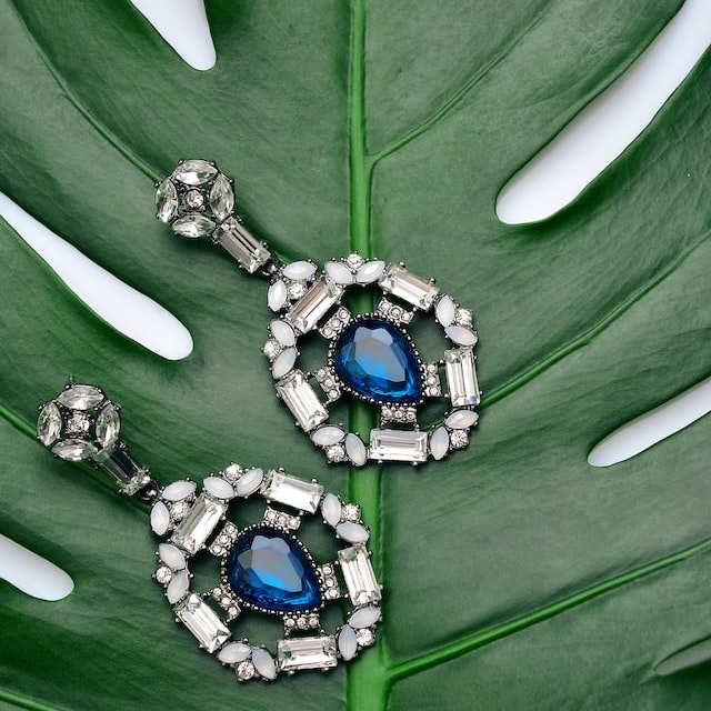A pair of earrings on a Monstera leave