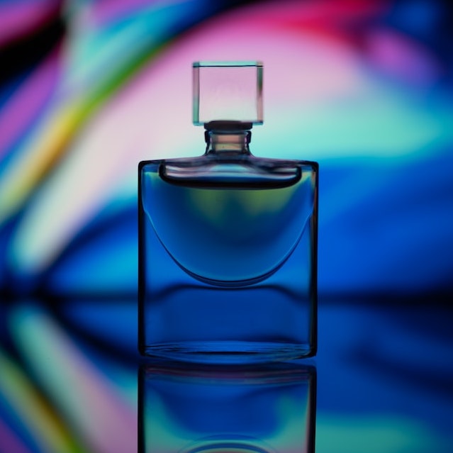 A photo of a perfume bottle with a colorful backdrop